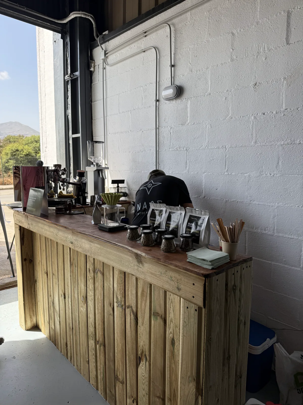 Barra de Naos Coffee montada en la nave de Valkyria Box antes de abrir, con la cafetera, el molinillo, la V60 y las bolsas de café colocadas.