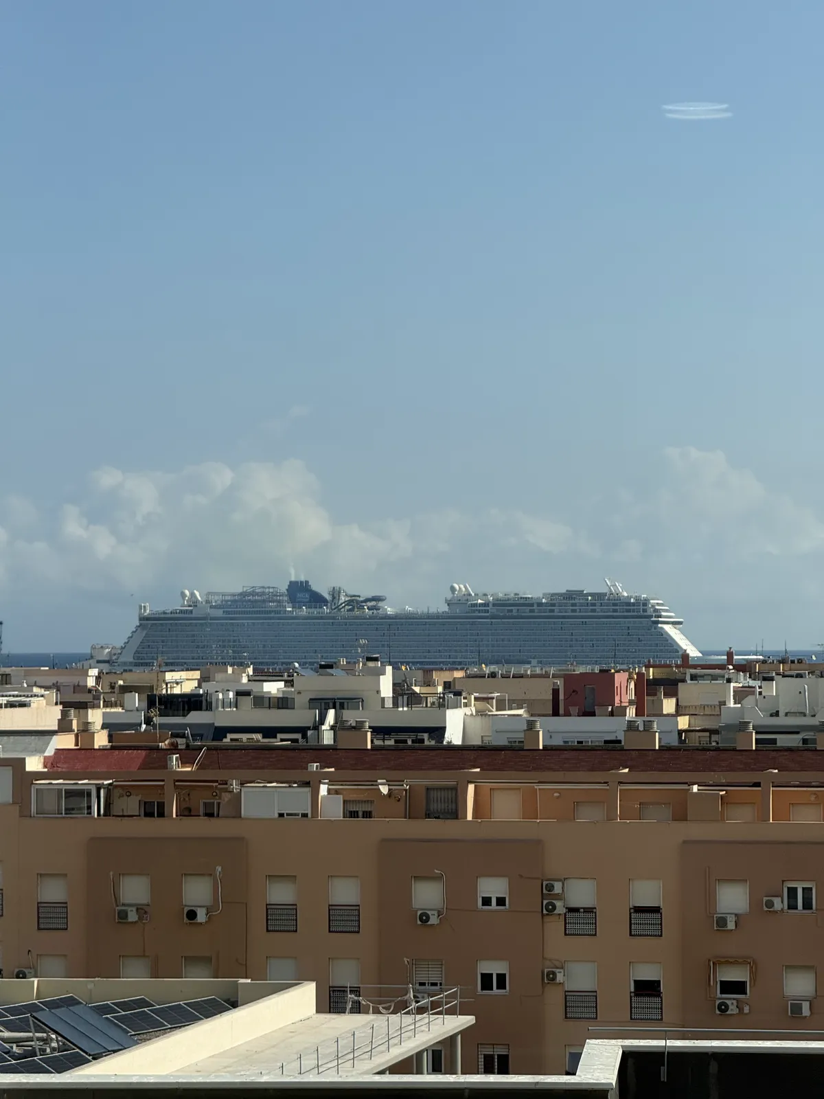 El crucero Norwegian Escape atracado en el puerto de Melilla, visto por encima de los edificios del centro.