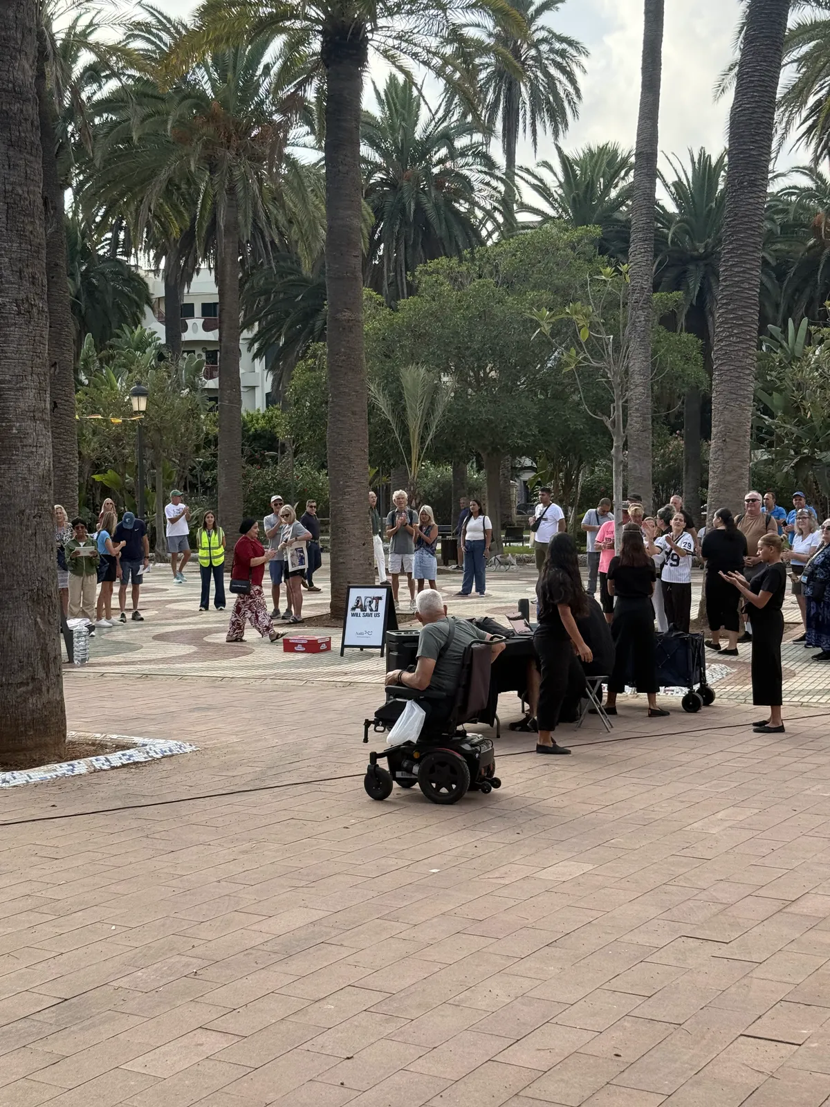Grupo de la Asociación NANA preparándose en el Parque Hernández de Melilla antes de su espectáculo, con los primeros visitantes alrededor.