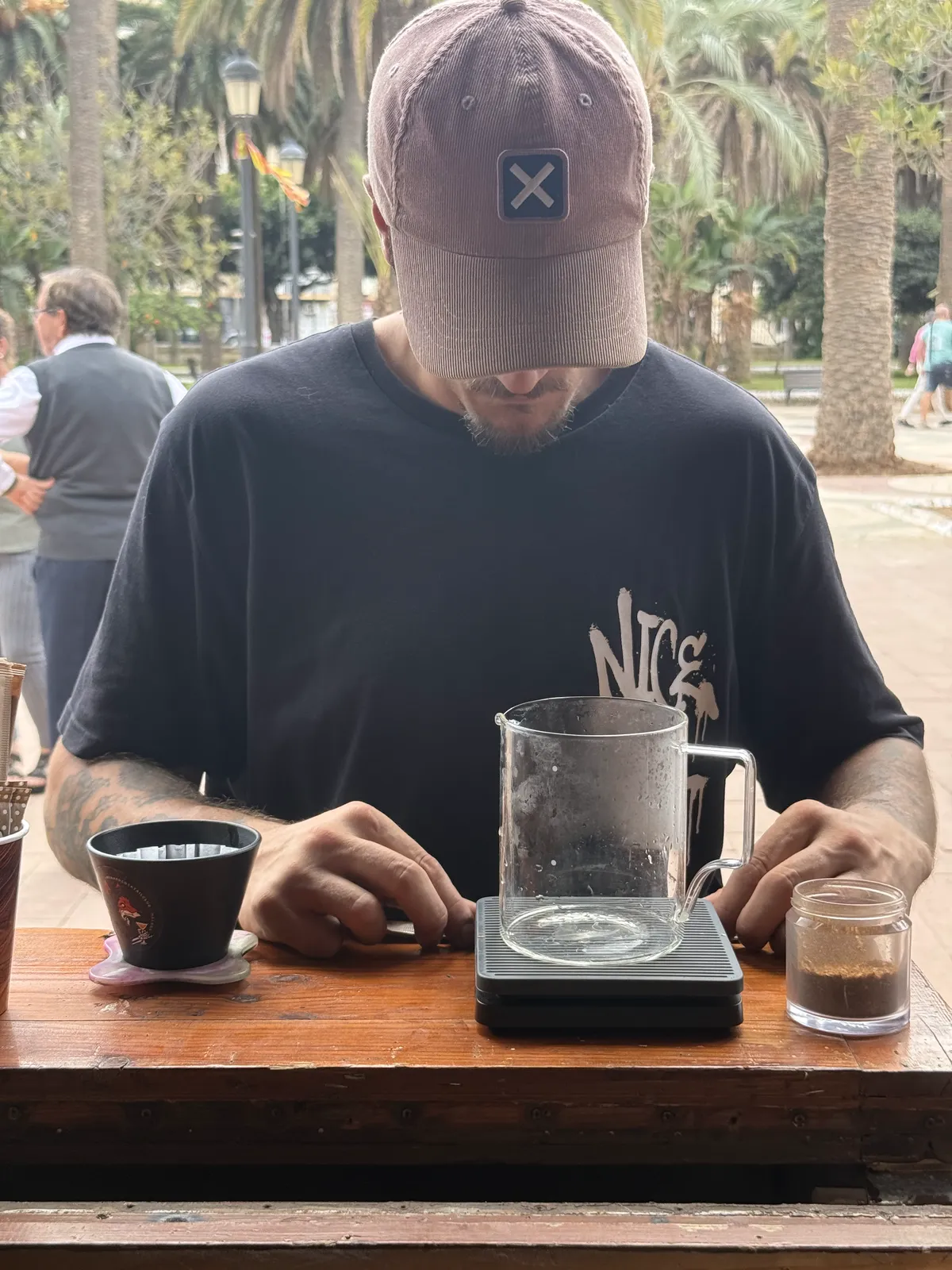 Barista de Naos Coffee preparando un café de filtro sobre la báscula, con el Parque Hernández de fondo.